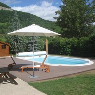 Piscine en montagne, entourée de sapins, avec un pourtour en lame composite marron chocolat, alliant nature et modernité