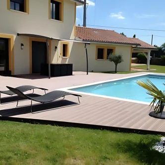 Maison traditionnelle avec terrasse en lames composites marron chocolat, piscine, transats, palmiers pour une ambiance estivale