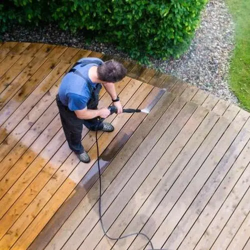 un homme entretenant sa terrasse en bois naturelle